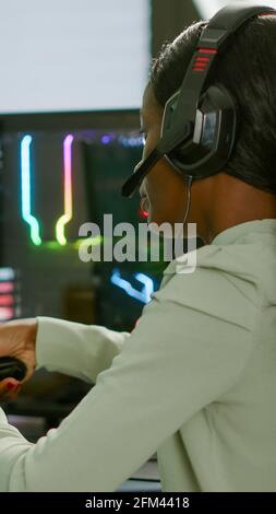 Pro african Gamer spielen Online-Weltraum-Shooter-Spiel auf einem leistungsstarken Computer mit Wireless-Controller und Headset. Wettbewerbsfähige Cyber-Spieler Frau Durchführung Videospiel-Turnier verwenden professionelle Joystick Stockfoto