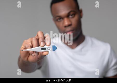 Mann hält Thermometer an die Kamera Stockfoto