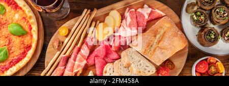 Italienisches Food-Panorama mit Antipasti und Pizza, von oben geschossen, mit Artischocken Stockfoto