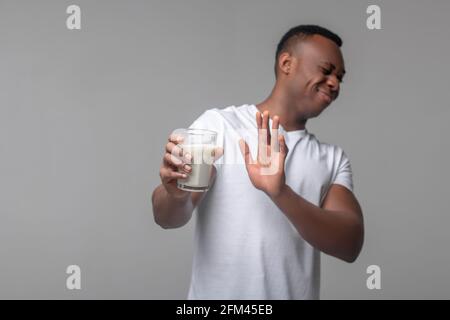 Mann mit Grimasse weigert sich, ein Glas Milch zu trinken Stockfoto