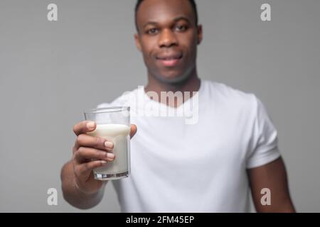 Mann streckt seine Hand mit einem Glas Milch Stockfoto