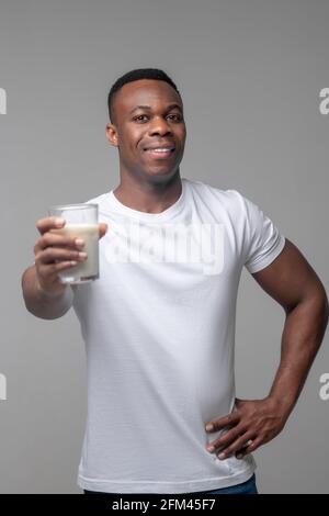 Fröhlicher Mann, der ein Glas Milch nach vorne hält Stockfoto