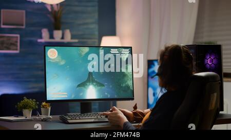 Back Shot von Pro Gamer spielen Online-Weltraum-Shooter-Spiel auf einem leistungsstarken Computer mit Wireless-Controller. Wettbewerbsfähige Cyber-Spieler Frau Durchführung Videospiel-Turnier verwenden professionelle Joystick Stockfoto