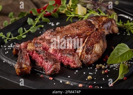 Kalbssteak in Scheiben mit Gewürzen und Kräutern auf Holzboden Stockfoto
