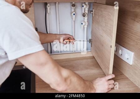 Mann montiert Türscharnier an der Tür der Küchenmöbel Stockfoto