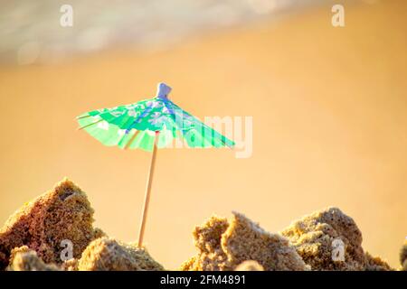 Kleiner Sonnenschirm aus Papier für Cocktail Stand in Sand auf Sand Stockfoto