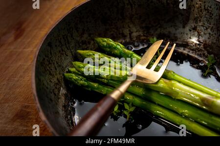 Spargelspieße in Bratpfanne auf Holzhackbrett, gutes Essen, gesundes Essen. Stockfoto