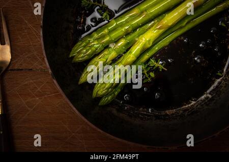 Spargelspieße in Bratpfanne auf Holzhackbrett, gutes Essen, gesundes Essen. Stockfoto