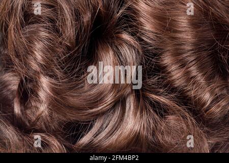 Braune Haarstruktur. Welliges, langes lockiges, hellbraunes Haar als Hintergrund. Haarverlängerung, Materialien und Kosmetik, Haarpflege. Frisur, Haarschnitt Stockfoto