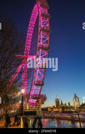 Das London Eye erleuchtete in der Nacht mit rot Big Ben im Hintergrund Stockfoto