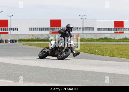 Uljanowsk, Russland - 10. Juni 2017. Motorrad-Rennfahrer in schwarzer Uniform, der sich in eine schnelle Kurve auf der Strecke lehnt Stockfoto