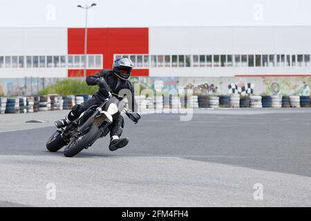 Uljanowsk, Russland - 10. Juni 2017. Motorrad-Rennfahrer in schwarzer Uniform, der sich in eine schnelle Kurve auf der Strecke lehnt Stockfoto