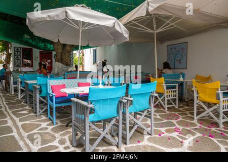 Paros, Griechenland - 28. September 2020: Farbenfrohe Tische und Stühle in einem griechischen Restaurant in der Stadt Parikia auf der Insel Paros. Stockfoto