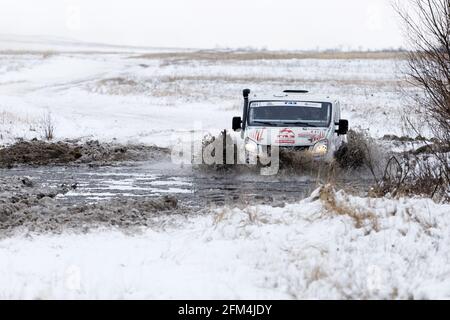 Uljanowsk, Russland - 09. Dezember 2017. Rally razzia 'Hills of Russia'. Allradantrieb-Rallye-Fahrzeug überwindet einen halb gefrorenen Teich zwischen schneebedeckten Feldern und Hügel Stockfoto