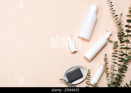 Flaschen von Essenz oder Serum mit natürlichen Eukalyptusblättern auf beigem Hintergrund. Naturkosmetik und Spa Flat Lay Stockfoto