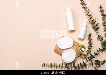 Flaschen von Essenz oder Serum mit natürlichen Eukalyptusblättern auf beigem Hintergrund. Naturkosmetik und Spa Flat Lay Stockfoto