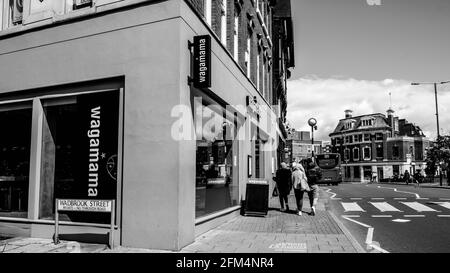 Kingston upon Thames London Großbritannien, 04 2021. Mai, Schwarz-Weiß-Bild drei anonyme Mädchen oder Frauen, die an EINEM Wagamama Asian Food Restaurant vorbeigehen Stockfoto