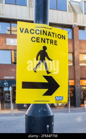 Gelbes NHS-Richtungsschild, das auf das Impfzentrum COVID-19 im Stadtzentrum von Woking, Surrey, England, zeigt Stockfoto