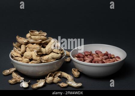 Eine Schüssel mit geschälten Erdnüssen und eine weitere voll Erdnussschalen Stockfoto