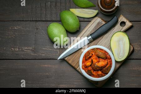 Rohe Mangobeize oder aam ka aachar oder achar in Eine weiße Schale und auf einem hölzernen Hintergrund Thema mit Mangos Stockfoto