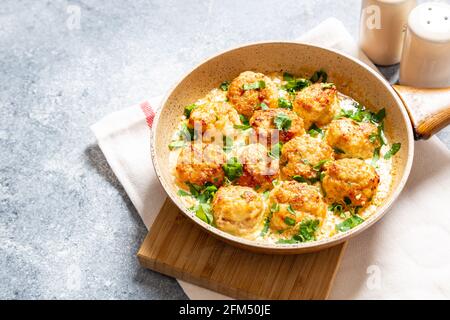 Fleischbällchen in weißer Soße in einer Pfanne auf grauem Hintergrund, bequeme hausgemachte gesunde Lebensmittel Stockfoto