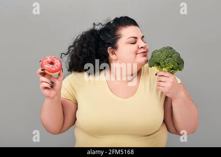 Übergewichtige Frau wählt gesunde Lebensmittel für die richtige Ernährung und Gewichtsverlust. Diät-Konzept Stockfoto