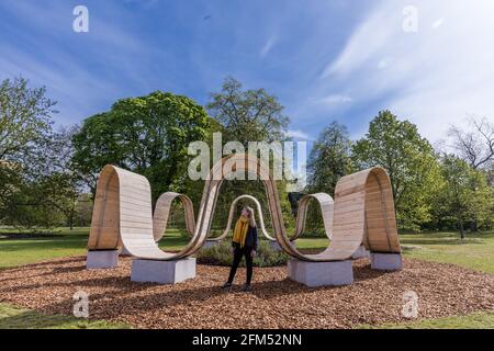 Kew Gardens, Richmond, Großbritannien. Mai 2021. Sommer bei Kew: Die geheime Welt der Pflanzen. Model genießt die immersive Skulptur 'Please be seated' von Paul Cocksedge. Das immersive Sommerfestival umfasst die wunderbare Welt der Pflanzenbiodiversität durch neu in Auftrag gegebene interaktive Kunstinstallationen mit Musik, Klang und Farbe. Im Zentrum des Festivals stehen sechs riesige ‘„Plantscapes“, die über die Kew Gardens verteilt sind und die britische Artenvielfalt feiern und vor ihrem Niedergang warnen. Amanda Rose/Alamy Live News Stockfoto