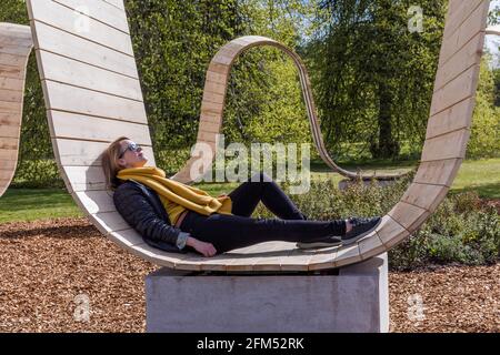 Kew Gardens, Richmond, Großbritannien. Mai 2021. Sommer bei Kew: Die geheime Welt der Pflanzen. Model genießt die immersive Skulptur 'Please be seated' von Paul Cocksedge. Das immersive Sommerfestival umfasst die wunderbare Welt der Pflanzenbiodiversität durch neu in Auftrag gegebene interaktive Kunstinstallationen mit Musik, Klang und Farbe. Im Zentrum des Festivals stehen sechs riesige ‘„Plantscapes“, die über die Kew Gardens verteilt sind und die britische Artenvielfalt feiern und vor ihrem Niedergang warnen. Amanda Rose/Alamy Live News Stockfoto