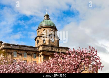 DR GRAUT KRANKENHAUS ELGIN MORAY SCHOTTLAND MIT ROSA KIRSCHBLÜTE PRUNUS SERRULATA VOR DEM HAUPTGEBÄUDE UND GRÜN KUPPEL MIT UHR Stockfoto
