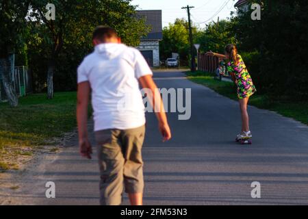 Unschärfe glücklich junge Mädchen und Jungen spielen auf dem Skateboard auf der Straße. Sie legte die Waffen an die Seiten kaukasische Kinder reiten Penny Board, üben Stockfoto