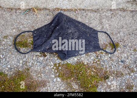 Schwarze Stoff Gesichtsmaske auf der Straße weggeworfen. Stockfoto