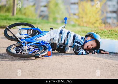 Ein kleines Kind fiel vor Schmerzen weinend und schreiend von einem Fahrrad. Stockfoto