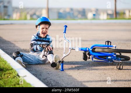 Ein kleines Kind fiel vor Schmerzen weinend und schreiend von einem Fahrrad. Stockfoto