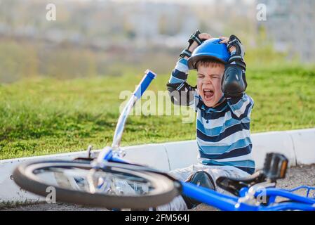 Ein kleines Kind fiel vor Schmerzen weinend und schreiend von einem Fahrrad. Stockfoto