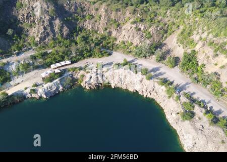 Felsige Ufer des Radon Lake an einem sonnigen Sommermorgen. Luftaufnahme eines alten überfluteten Granitsteinbruchs. Ein malerischer Teich. Stockfoto