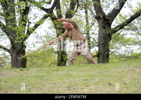 Ein älterer asiatischer Amerikaner, wahrscheinlich Chinese, macht Tai-Chi-Übungen mit einem langen Stock. Auf einem Hügel in einem Park in Queens, New York City. Stockfoto