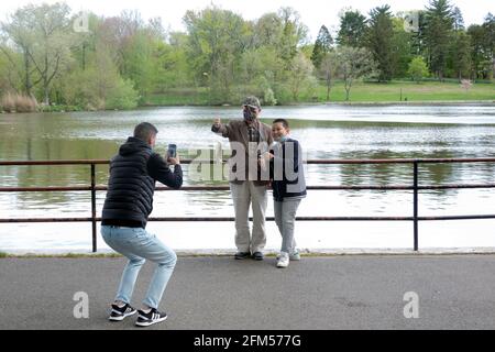 Ein stolzer Junge posiert mit seiner Familie, die den Fisch zeigt, den er gefangen hat. Am See im Kissena Park, Flushing, Queens, New York City. Stockfoto