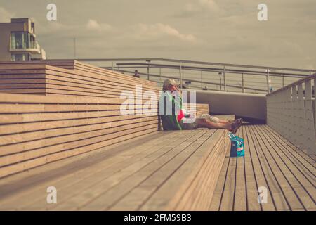 Ein älteres Paar, das sich auf einer Terrasse am Yachthafen mit Blick auf das Meer entspannt und im Sommer einen Imbiss hat Stockfoto