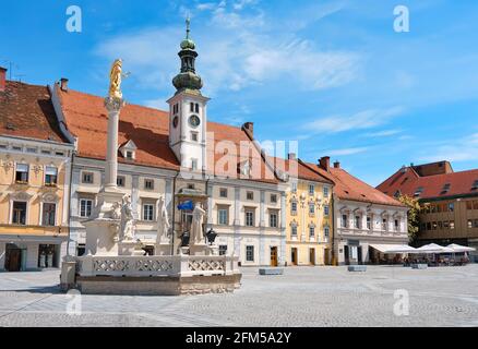 Stadtzentrum von Maribor, Slowenien. Rathaus und Pestdenkmal auf dem Maribor Hauptplatz. Blauer Himmel, helles Tageslicht, Panoramabild. Stadtbild von Stockfoto