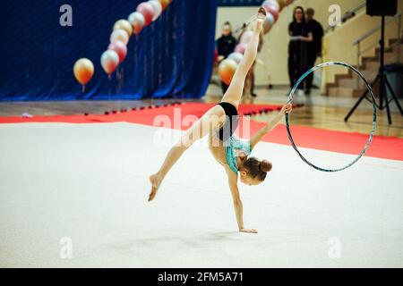 Ein Turnerin-Mädchen führt mit einem Reifen. Flexible Athlet führt einen Handstand bei Wettbewerben Stockfoto