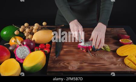 Foto von Frau schneidet Drachenfrucht auf Holzbrett Stockfoto