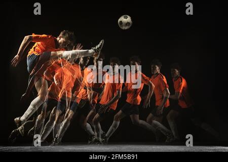 Junger männlicher Fußballspieler in Bewegung und Action in gemischtem Licht auf dunklem Hintergrund. Stockfoto