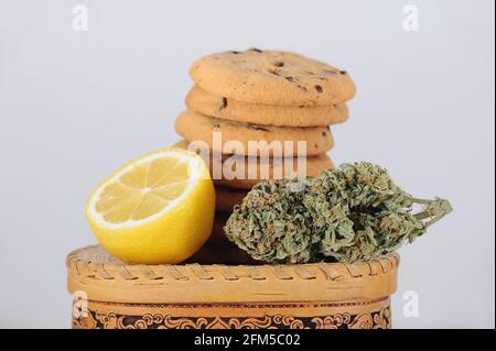 Süßigkeiten mit CBD-Öl. Marihuanaknospen auf weißem Hintergrund. Cannabisblüten und Schokoladenkekse aus der Nähe. Stockfoto