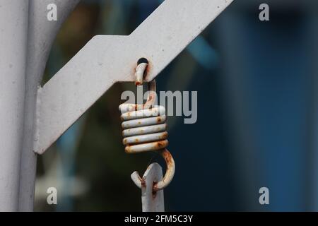 Alte rostige Metallfeder auf einem Schaukelstuhl im Garten. Stockfoto
