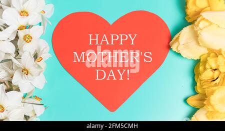 Weiße Narzissen und gelbe Tulpen mit Herz und der Inschrift Happy Mother's Day. Grünes schönes Banner für den Urlaub. Stockfoto