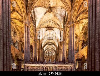 Das gotische Langhaus der Kathedrale von Barcelona mit hohen Steinsäulen, Kreuzrippengewölben und einem verzierten Chorgitter, Katalonien, Spanien. Stockfoto