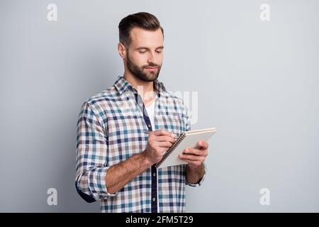 Portrait von attraktiven fokussierten Kerl tragen kariertes Hemd Schreibplan Strategie isoliert über grauem pastellfarbenem Hintergrund Stockfoto