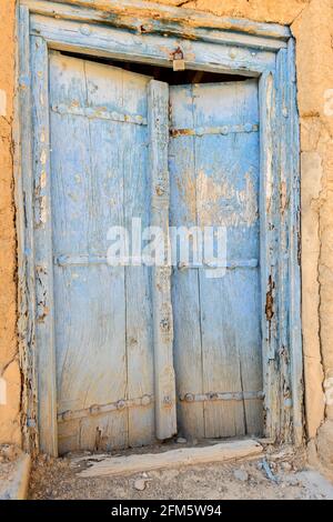 Al Hamra. Region Ad Dakhiliyah, Oman. Holztür im alten Teil der Stadt mit verlassenen zerstörten Häusern. Stockfoto