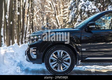Moskau, Russland - 15. Februar 2021: Kia Mohave 2021 schwarz SUV steht auf der Straße im Winterwald, Schneeverwehungen. Seitenansicht Stockfoto