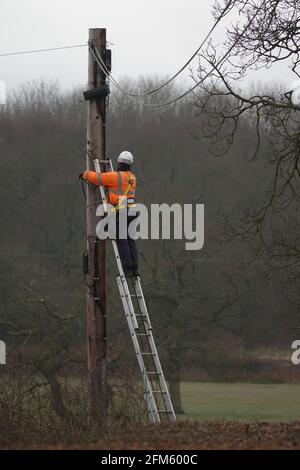 British Telecom OpenReach-Ingenieur, der oben in der Höhe arbeitet Eines Telegrafenmastes auf dem Land Stockfoto